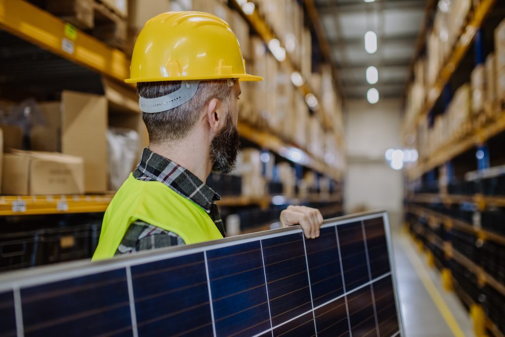 rear-view-of-warehouse-worker-carring-solar-panel